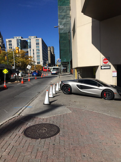 Car and wide traffic cones located on sidewalk.  View down city street.