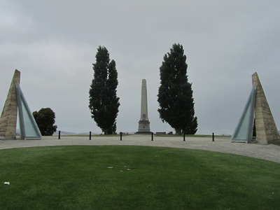 Monument in the distance with two large trees at each side.