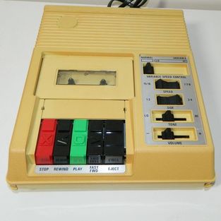 A portable four track cassette player is depicted.  Yellow in colour with control buttons.  These were common two decades ago to proivde people with vision loss access to audio recordings. 