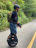 Person wearing backpack and helmet stands upright on electric unicycle