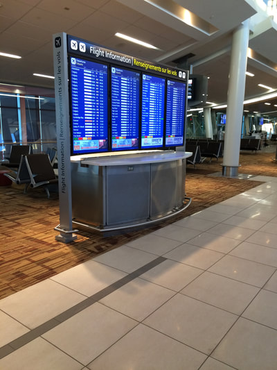 Large monitor at eye level in airport listing flight schedules. 