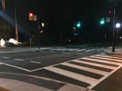 Intersection at night with crosswalks and textured curbs.