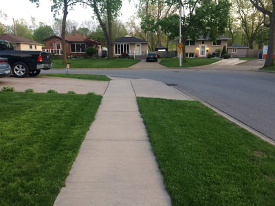 Sidewalk leading to street with grass on each side.