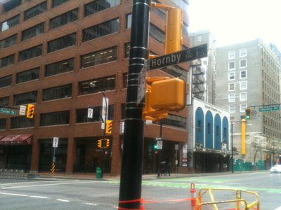 Post on street corner with traffic signals and street signs attached.